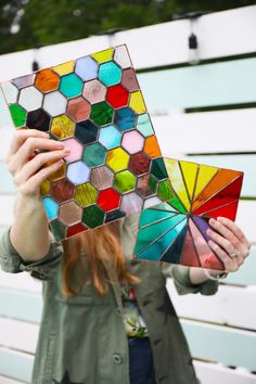 a woman holding up a multicolored piece of art