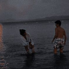 two people standing in the water at night