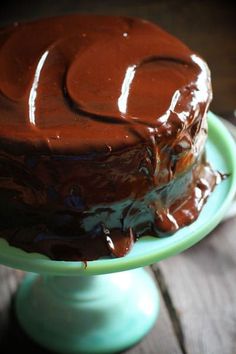 a chocolate cake sitting on top of a green plate covered in frosted icing