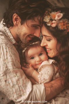 A happy family portrait featuring a smiling baby nestled between a mother and father, all sharing a joyful moment together. The parents are dressed in light-colored, patterned clothing, while the mother wears a floral headband. The warm lighting enhances the affectionate atmosphere of the image. Samantha Cute, Simple Girl Names, One Syllable Girl Names