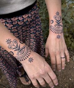 two women with tattoos on their hands and one is holding the other's hand