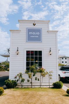 the outside of a coffee shop with cars parked in front of it and blue skies above