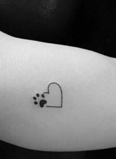 a black and white photo of a dog paw with a heart tattoo on the arm