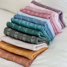 a stack of folded sheets sitting on top of a bed next to pillows and blankets