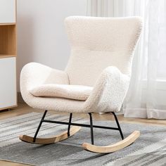 a white rocking chair sitting on top of a rug