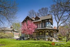 a large house sitting in the middle of a lush green field with lots of trees