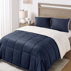 a blue and white comforter on a bed in a bedroom