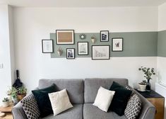 a grey couch sitting in front of a wall with pictures on the walls above it