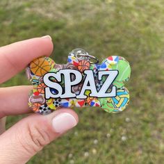 a hand holding a small badge with the word spaz on it