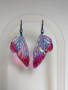 These Iridescent Pixie Wing Earrings are stunning and beautiful. To make these Fairy Wings, I start by creating a hand painted design. This design is then printed on transparent paper, and coated in layers of iridescent pigments. On all of my dangle earrings, I use hypoallergenic niobium ear hooks.  This material is pricier to work with, but safe for even the most sensitive ears. It has the added benefit of coming in beautiful colors, which are incorporated to become an integral design element. Pink Fairycore Earrings As Gift, Fairycore Pink Earrings For Gifts, Fairycore Pink Earrings As Gift, Iridescent Pierced Earrings As Gift, Unique Iridescent Earrings, Unique Iridescent Pierced Earrings, Fairycore Butterfly Earrings For Gift, Handmade Fairycore Drop Earrings, Unique Iridescent Earrings For Party