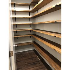 an empty walk - in closet with shelves and wood flooring on the side wall