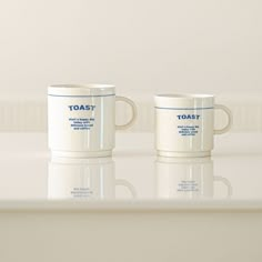 two white coffee mugs sitting on top of a counter