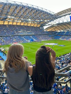 two women looking at a soccer field from the bleachers in an empty stadium