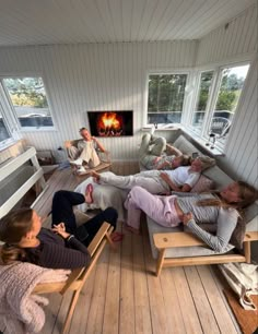 four people laying on couches in front of a fire place