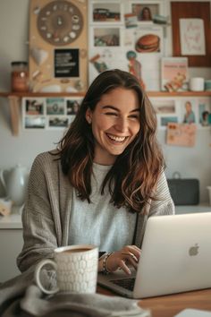 a woman sitting at a table with a laptop computer in front of her and smiling