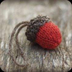 a red and gray knitted ball sitting on top of a wooden table next to a string