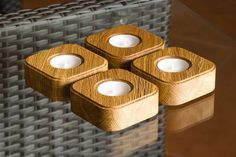 three tea light holders sitting on top of a glass table next to a wicker chair