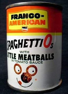 a can of spaghetti with little meatballs in tomato sauce on a black tablecloth