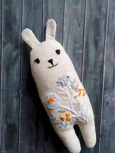 a stuffed animal hanging from the side of a wooden fence with flowers and leaves on it