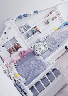 there are two beds with stuffed animals on them in this room, one is white and the other is blue