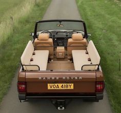 the back end of a brown and tan truck parked on top of a dirt road