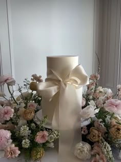 a white vase with flowers and a bow on it