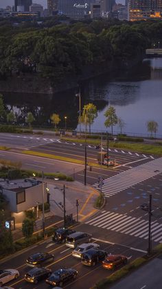 cars are parked on the street in front of an intersection with water and city buildings