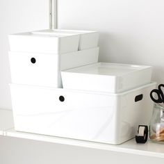 three white storage containers sitting on top of a shelf next to scissors and other items