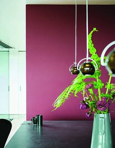 a vase filled with flowers sitting on top of a wooden table next to a red wall