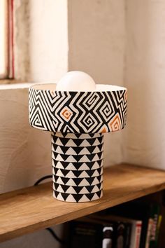 a black and white vase sitting on top of a wooden shelf