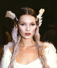 a woman with long hair and angel wings on her head, wearing a white dress