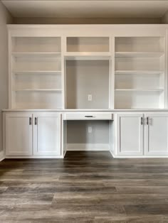 an empty room with white cabinets and wood floors