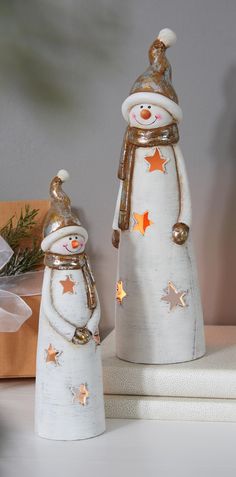 two snowmen standing next to each other on top of a white table with presents