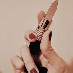 a woman's hand holding a lipstick and a knife