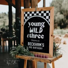 a sign that says young wild and three with candles on it in front of some plants