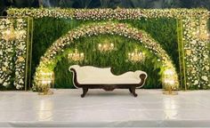 a white couch sitting in front of a lush green wall with flowers and greenery