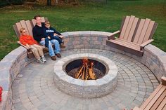 two adults and a child sitting around a fire pit