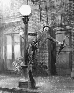 a man standing on top of a lamp post in the rain with his arms outstretched