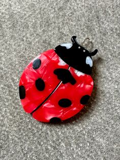 a red and black ladybug pin sitting on top of a carpeted floor