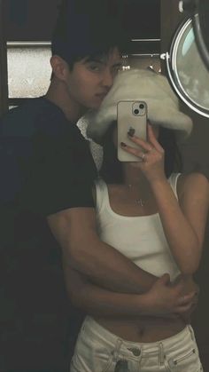 a man and woman taking a selfie in front of a mirror