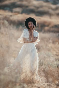 a woman wearing a white dress standing in tall grass