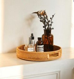 a basket with some bottles and flowers in it sitting on a counter next to a mirror