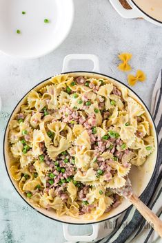 a skillet filled with pasta and peas on top of a table next to other dishes