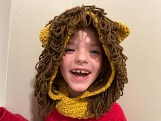 a young boy wearing a lion costume with dreadlocks and a red shirt is smiling at the camera