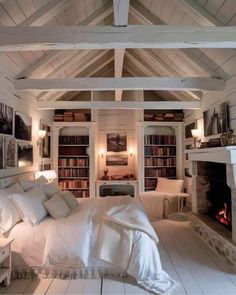 a bedroom with white walls and flooring has a fireplace in the corner, bookshelves on either side