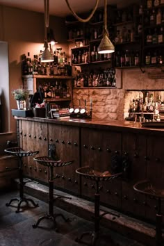 an old fashioned bar with stools in front of it and bottles on the shelves