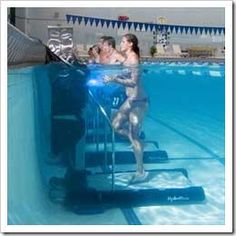 a man and woman standing in an indoor swimming pool next to the edge of a ladder