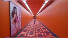 a woman is walking down an orange hallway