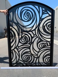 a black and white gate with swirls on it in the middle of a parking lot