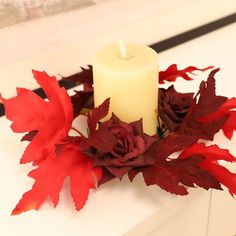 a candle and some red leaves on a table